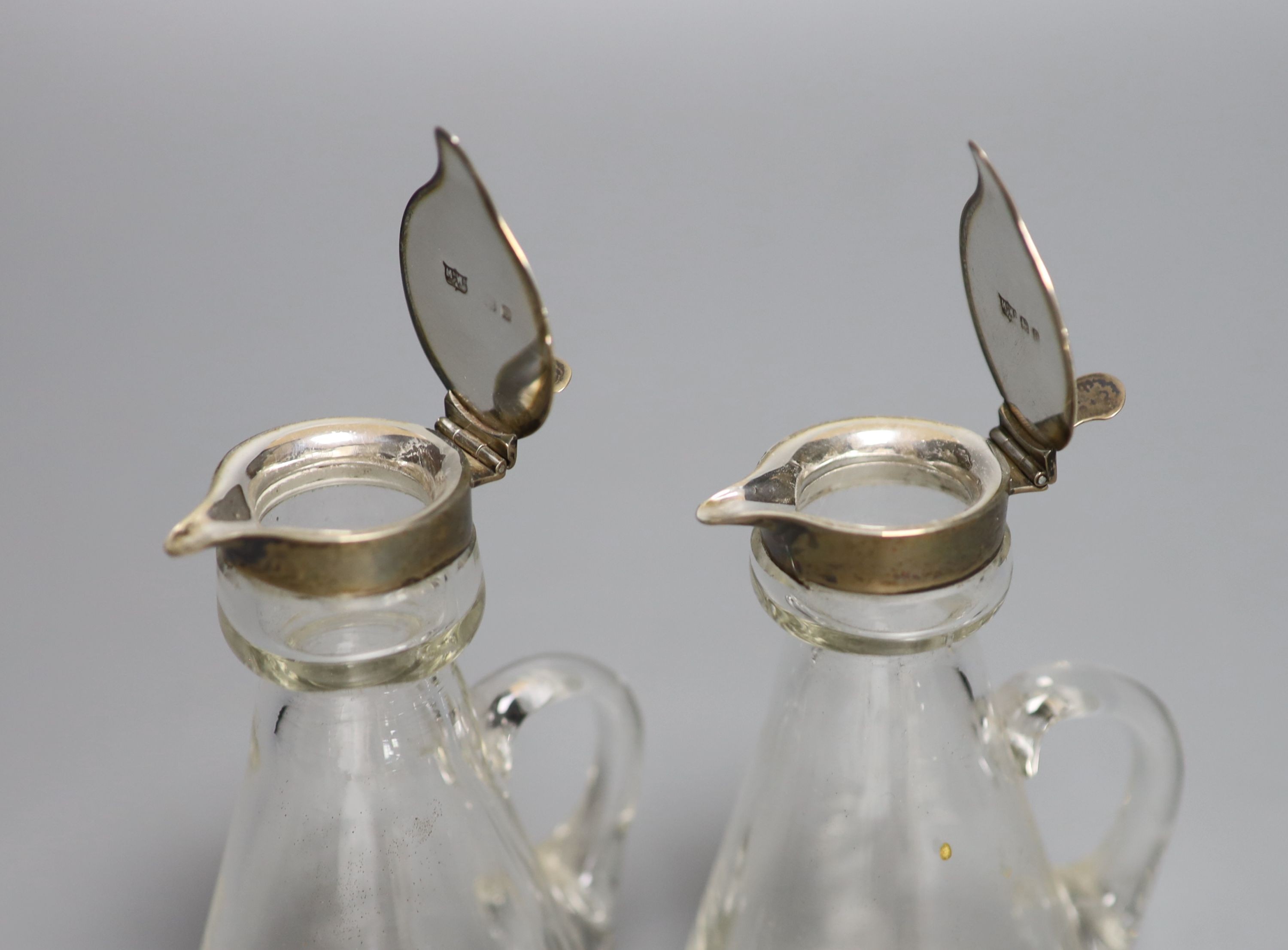 A near pair of George V silver mounted glass whisky tots (one a.f.), Mappin & Webb, Birmingham, 1913, one with engraved crest to cover, 12.1cm.